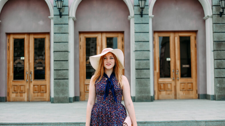 girl on a city street with a hat and handbag
