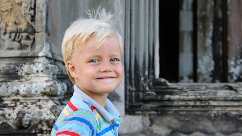 Cute little boy 4 years old blond hair sitting outdoor. Angkor, Cambodia