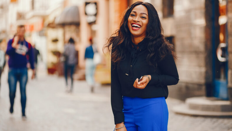 Elegant black woman standing in a summer city. Businesswoman in a blue pants