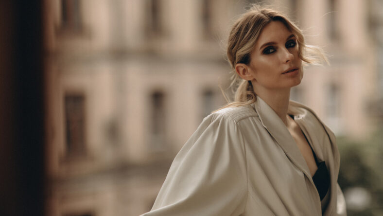 Fashionable portrait of a stylish blonde woman in elegant totall beige look leather trench coat and smoky eyes makeup in the outdoor. Spring - autumn fashion concept. Soft selective focus.