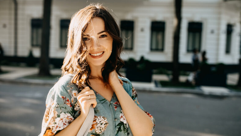 Young cheerful woman walking on city streets on summer day.
