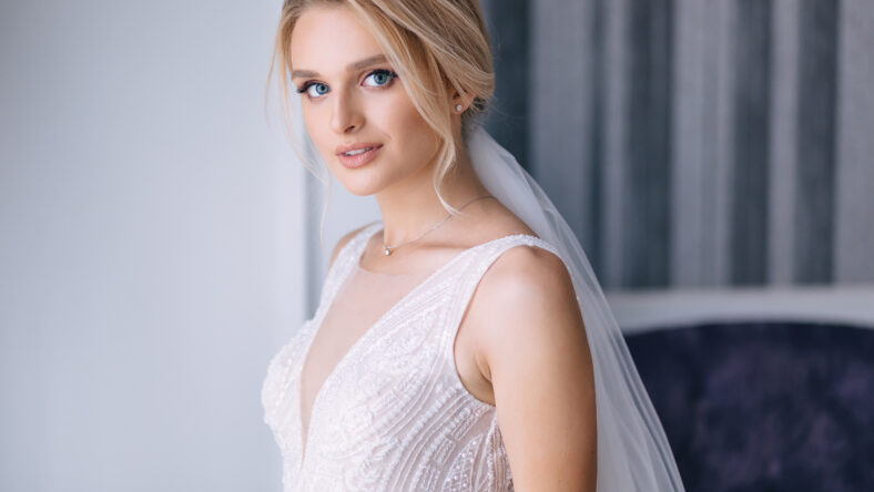 beautiful bride with blonde hair in elegant wedding dress posing in the room on wedding morning