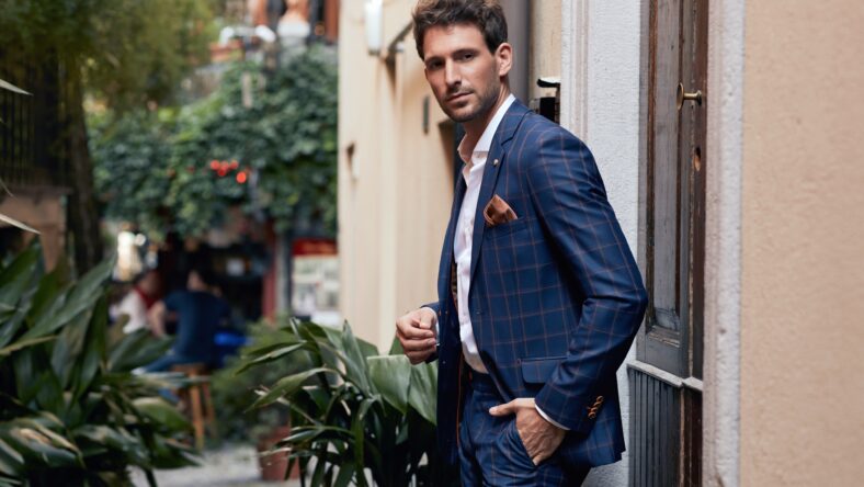 Young handsome man in classik checked suit standing on the street