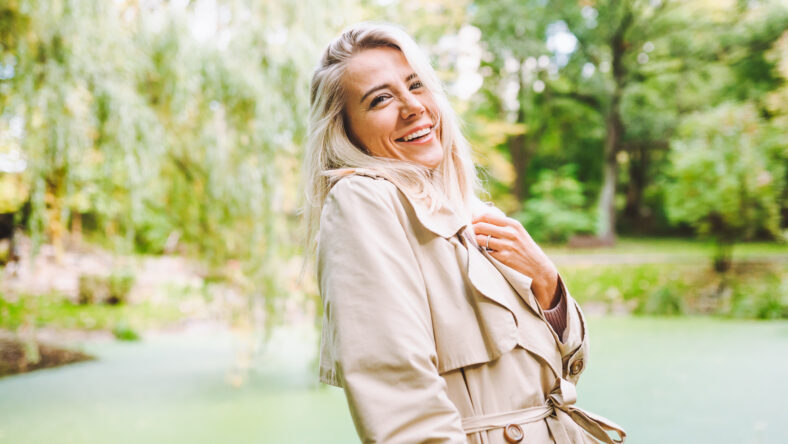 Caucasian blonde woman smiling happily on sunny summer or spring day outside walking in park