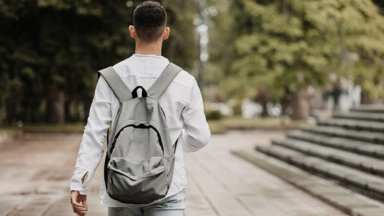 Young student going to university. Shot from behind.