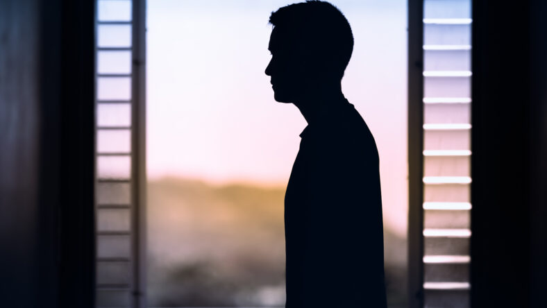Young thoughtful man looking out his window. Mind and thoughts concept.