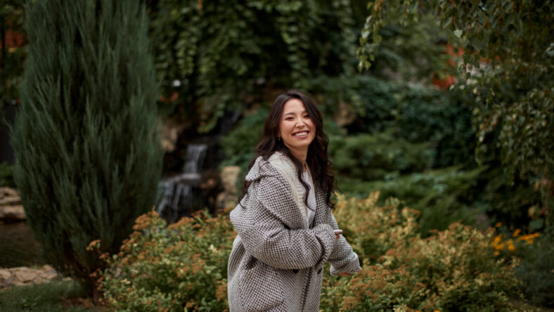 Close-up portrait of beautiful pretty asian kazakh brunette woman in plaid coat with charming smile walking along outdoors in park. Happy face. Autumn season. Cozy.