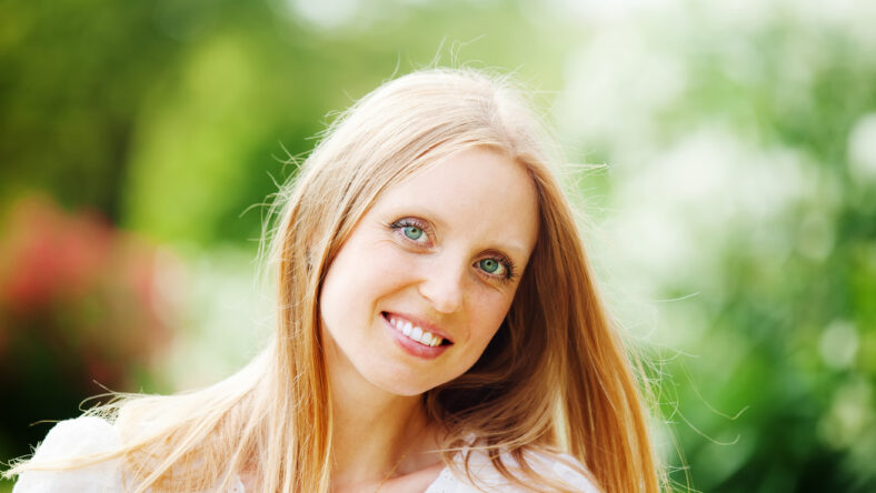 Smiling beautiful blonde middle-aged woman against nature background