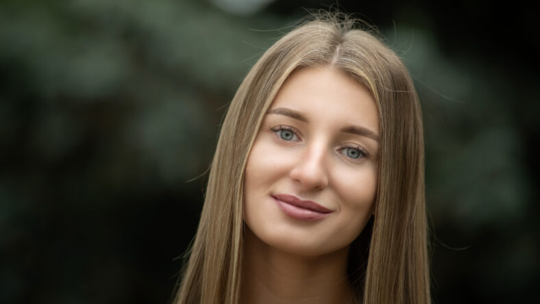 Portrait of a young beautiful blonde girl in a city summer park.