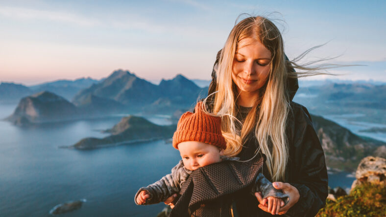 Mother hiking with baby carrier healthy lifestyle outdoor family time travel in Norway summer vacations scandinavian woman with child in mountains of Lofoten islands aerial view