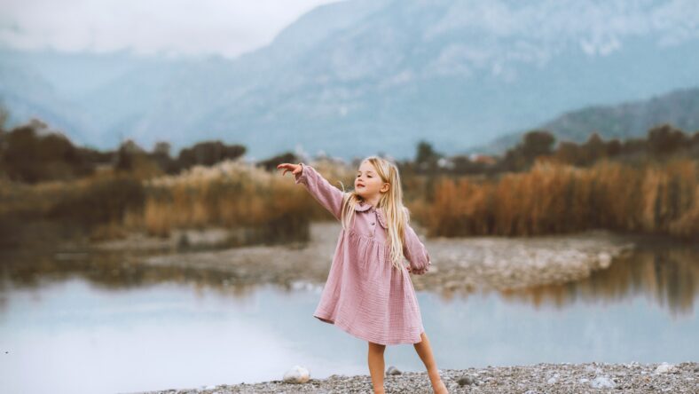 Child girl walking dancing barefoot outdoor 4 years old stylish kid wearing organic muslin dress fashion clothing family lifestyle lake and mountains harmony with nature