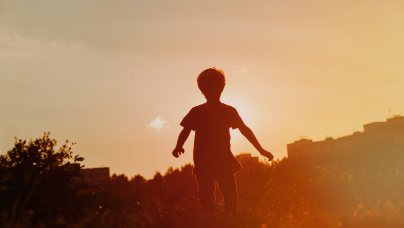 silhouette of little boy enjoy running at sunset