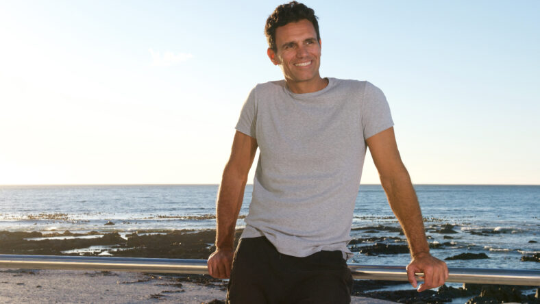 Portrait of handsome middle age man smiling by sea