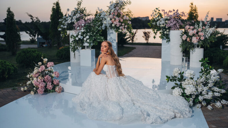 A beautiful and happy bride with long blonde hair in a evening wedding ceremony area decorated with flowers on the riverbank. wedding decor.