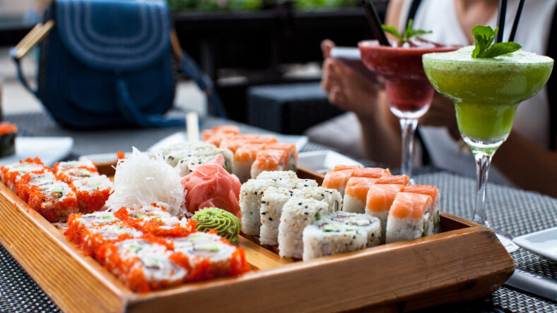 Woman eating sushi at restaurant in summer day.
