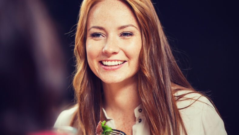 leisure, food, eating, people and holidays concept - happy woman with friends having dinner at restaurant