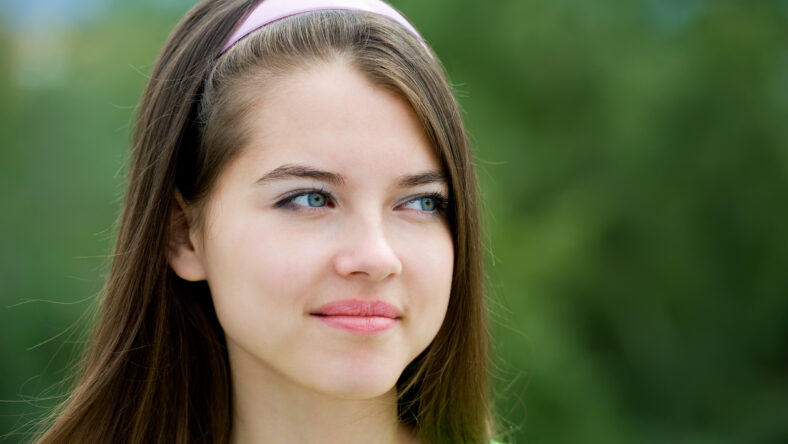 young beautiful Caucasian girl looks sideways, green background