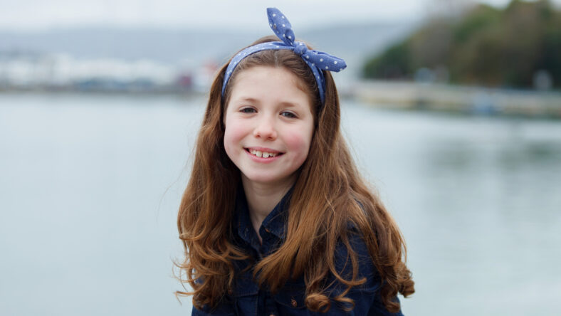 Beautiful girl with ten years old wearing a blue hair scarf enjoying of a beautiful day