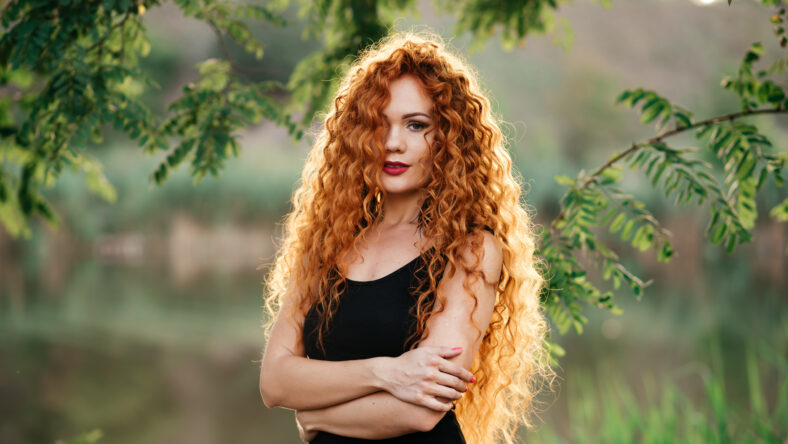 portrait af a beautiful redhead woman outdoors. stylish romantic young girl on a walk in the park. red hair and freckles
