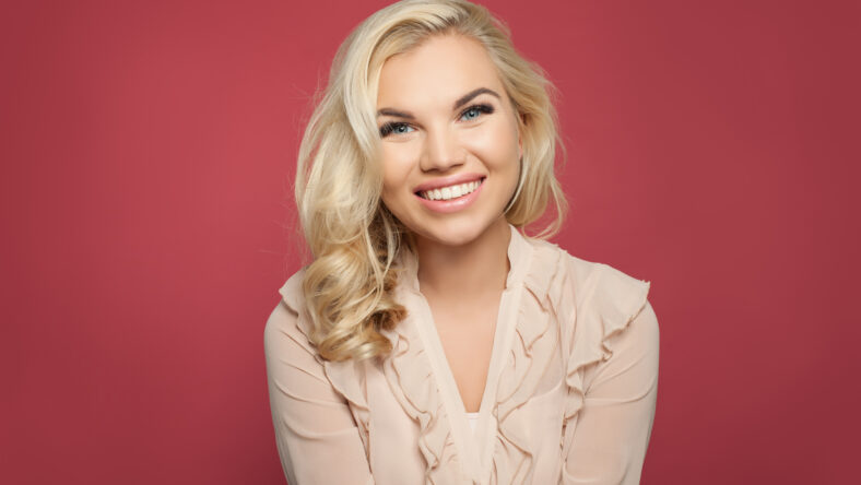 Beautiful young happy woman with curly blonde hair and cute smile portrait