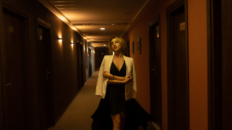 Luxury girl in black dress at night in the hotel corridor.