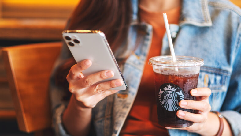 Jun 16th 2020 : A woman holding and using Iphone 11 Pro Max smart phone while drinking iced coffee at Starbucks coffee shop , Chiang mai Thailand