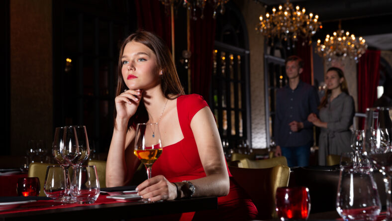 Single pretty woman with glass of wine sitting in luxury restaurant
