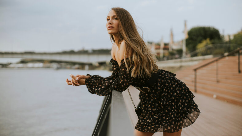 Pretty young long hair brunette woman standing on the riverside