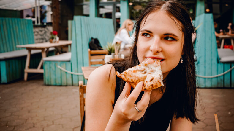 young teenager redhead girl eating pizza in cafe oudoor