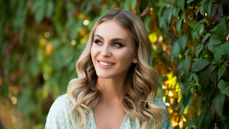 Portrait of young woman looking eways in summer park outdoor. Romantic girl with beauty face. Woman with romantic smile. Lifestyle, walk outdoors, enjoying life, positivity