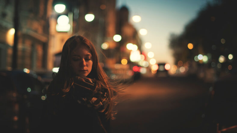 unhappy woman is walking alone on the night street