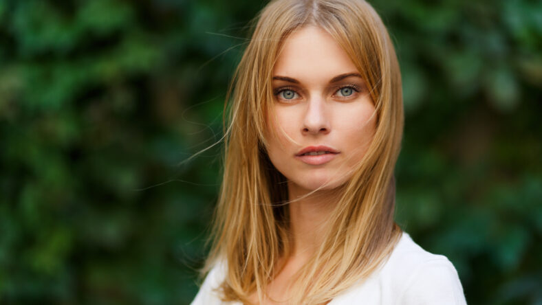 Portrait of beautiful woman on background green trees, close-up