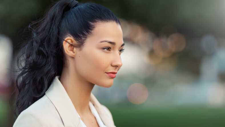 Woman smiling - side view portrait of happy lovely and beautiful mixed race asian caucasian young businesswoman in casual clothes outdoor in the city park