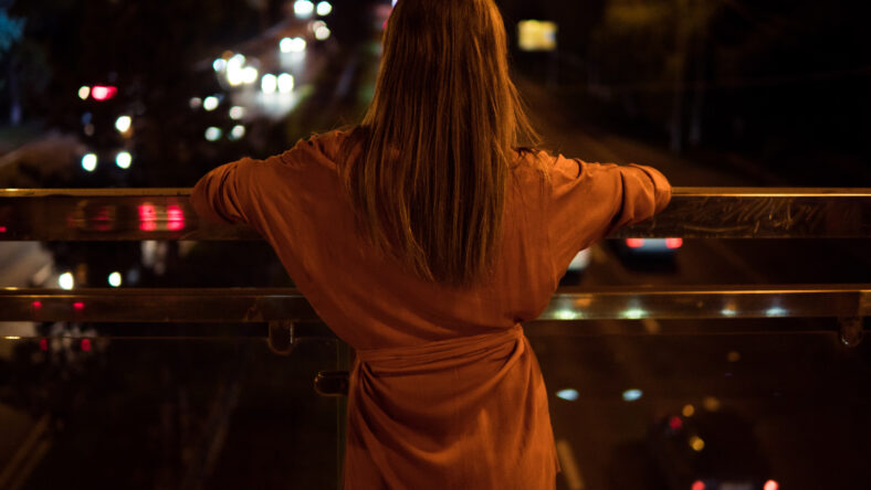 Young woman watching the view night city road from bridge.