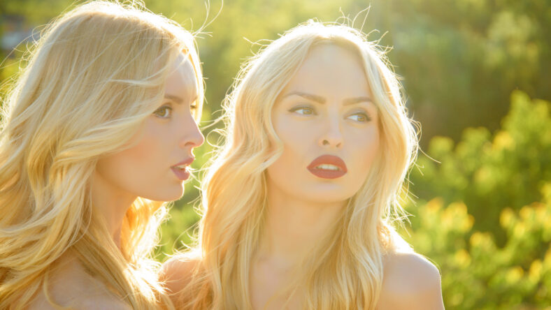 Twins in summer sunny weather. Beauty and fashion, look. Girls with sexy red lips, family and sisters. Freedom, relations and family values. Women with blonde hair and makeup outdoor.