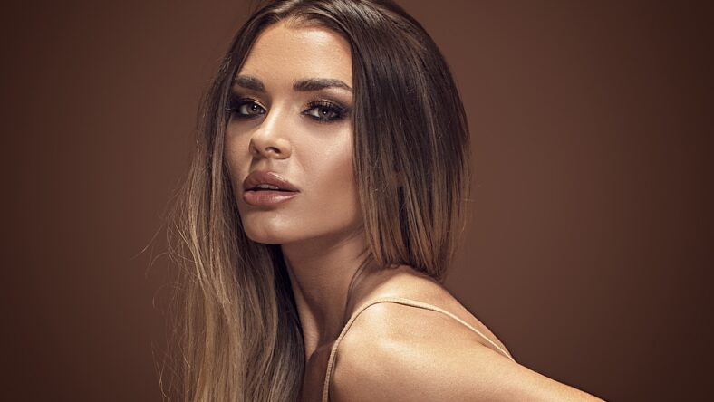 Beauty portrait of sensual caucasian brunette woman in glamour makeup and gold tanned skin.
