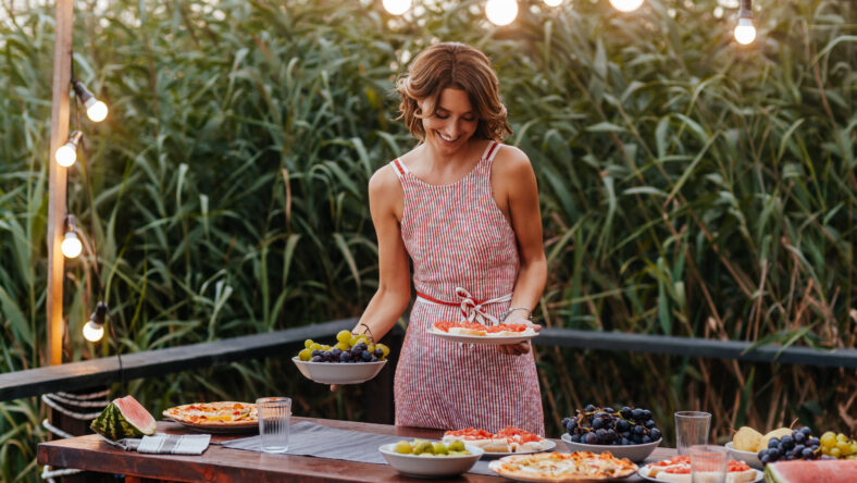 Beautiful woman setting up the table for outdoor dinner party.
