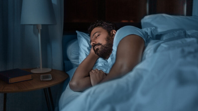 people, bedtime and rest concept - indian man sleeping in bed at home at night