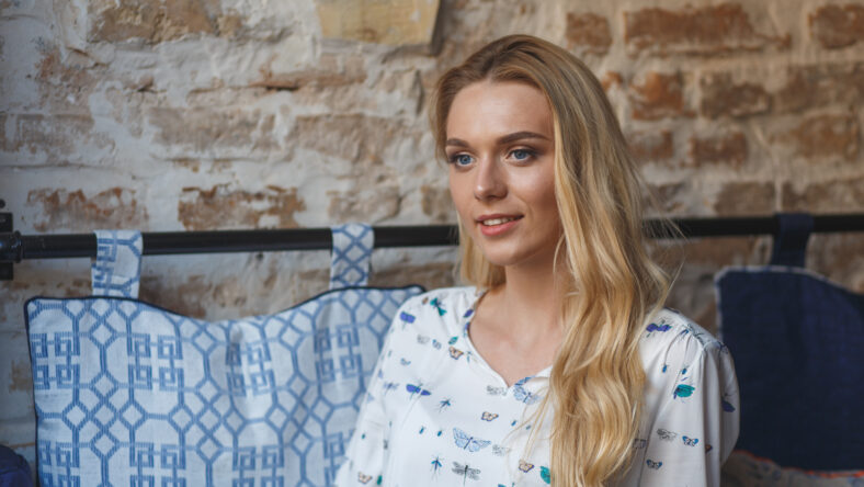 Young pretty woman wearing in white blouse resting on sofa in cafe