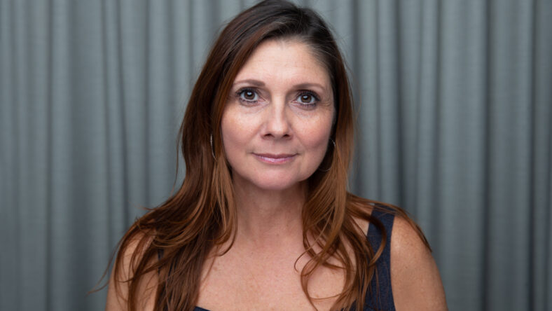 Simple portrait of a beautiful brunette middle aged 40+ 50+ year old woman with long hair looking at the camera making direct eye contact with a neutral expression