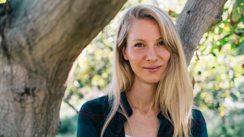 Portrait of a smiling young Caucasian woman in a natural setting.