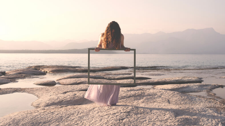 woman holding a frame that surreally reflects the landscape , concept of door to freedom