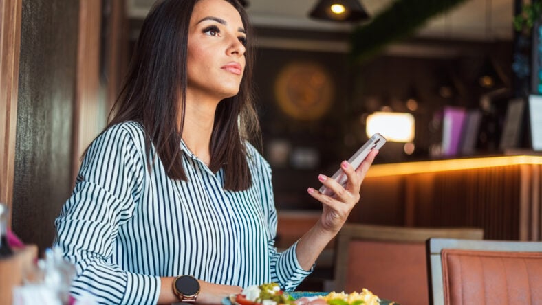 Businesswoman is holding a smartphone and looking