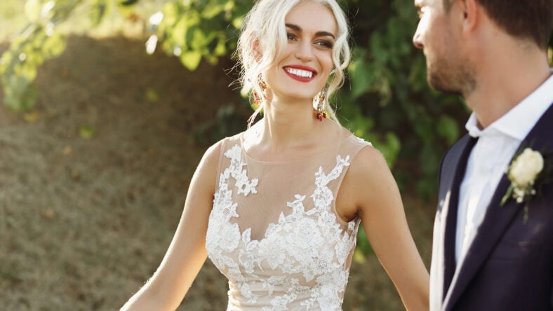 Shiny blonde bride looks at groom with