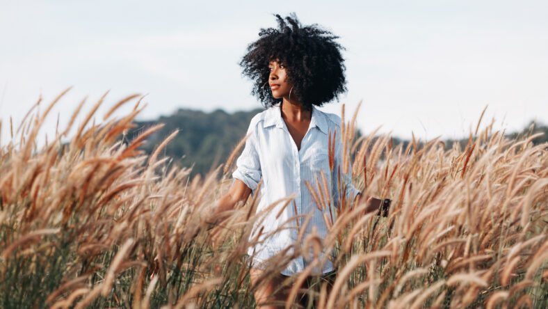 cheerful african american young woman on the field at sunset