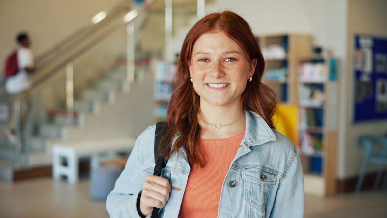 Education, portrait and smile of teen student on high school campus for development or growth. Future, learning and study with happy girl learner in academy hallway for knowledge or opportunity.