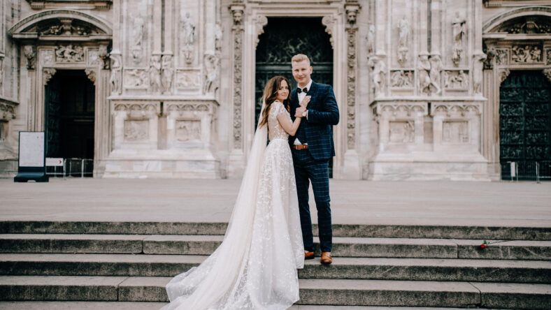 groom and bride posing in front of the church