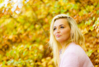 Blonde woman relaxing in autumnal park at