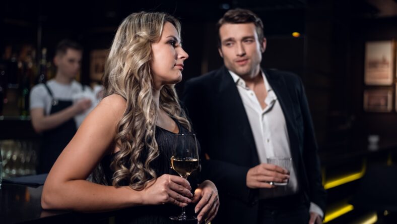 charming girl and handsome man with cocktail glasses in a nightclub.
