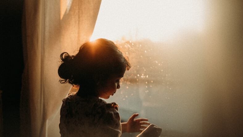 Little girl looking outside with beautiful light